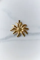 Collar con dije dorado en forma de girasol y tiento negro de 120 cm de largo.