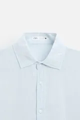 Camisa celeste de lino, de corte recto, manga larga y cuello clásico.