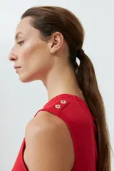 Musculosa roja de algodón con cuello redondo y botones decorativos en los hombros.