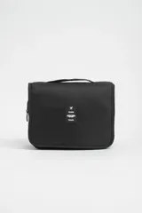 Necesser de viaje negro con cierre de cremallera y asa de transporte. Tiene un parche rectangular con el logo de un avión y la palabra "TRAVEL".