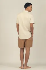 Camisa de manga corta color crema con textura, botones de madera y parche con logo.