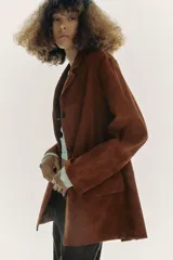 Blazer de cuero color marrón, con cuello solapa de muescas y manga larga. Tiene bolsillos con solapa en delantero, forro interior y cierre frontal con botones.