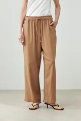 Pantalón de lino color marrón claro, de corte recto y tiro alto, con cintura elástica ajustable con cordón.