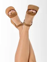 Sandalias de cuero color marrón con plataforma y taco de 8cm forrados en gamuza. Diseño con doble tira frontal y tira regulable al tobillo con hebilla metálica.