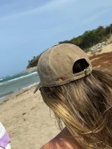 Gorra de béisbol color marrón con bordado frontal de la palabra "MILO" en color dorado.