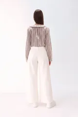 Camisa de algodón con estampado de rayas verticales en tonos beige y marrón. Presenta un cuello solapa con detalle de volados, cierre frontal con botones y mangas largas.