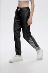 Pantalón de jogging color celeste con cintura elástica ajustable con cordón y puños elásticos. Presenta tres tiras verticales blancas en la parte inferior de la pierna.