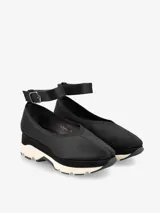 Zapato color marrón con base deportiva, pulsera al tobillo ajustable con hebilla metálica y puntera redondeada.