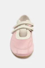 Zapato tipo bailarina de color rosa con efecto satinado, estilo deportivo, con doble tira ajustable con velcro en la parte delantera, detalle de pespuntes y acabado en punta redonda.
