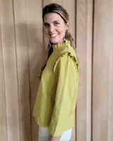 Blusa blanca con cuello mao con volados, mangas 3/4 con volados y calados con motivos florales.