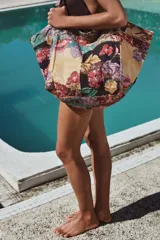 Maxi bolso de mano tipo tote bag con estampado floral multicolor sobre fondo amarillo.