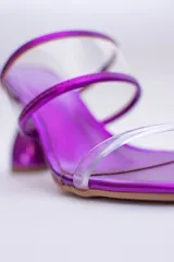 Sandalias plateadas con taco de forma geométrica y tiras transparentes.