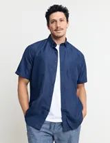 Camisa de manga corta azul con estampado de lunares blancos, cuello abotonado y bolsillo en el pecho.