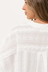 Camisa blanca con calados, escote en V, abotonada y manga 3/4.