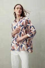 Camisa estampada con figuras geométricas en tonos azul, marrón y beige. Corte relajado, manga tres cuartos y botones al frente.