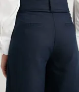 Pantalón pantacourt azul marino de lino y algodón, con cintura alta, pliegues delanteros, bolsillos laterales y cierre frontal con cremallera y botones.