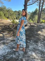 Vestido midi de seda con estampado floral en tonos azul y blanco, escote en V y mangas cortas.