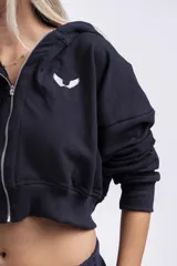 Campera corta negra con capucha, cierre frontal con cremallera y logo de alas blancas bordado en el pecho.
