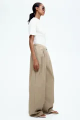Pantalón color beige de corte ancho, con pinzas delanteras, cintura alta con elástico y bolsillos laterales.