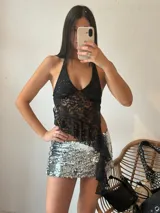 Top negro de encaje con escote halter y volados asimétricos.