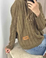 Sweater celeste de punto con diseño de trenzas verticales en color lila. Corte crop y etiqueta de cuero en el frente.