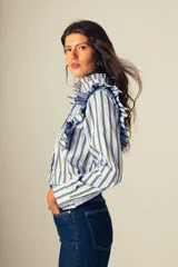 Camisa celeste a rayas verticales amarillas, con cuello alto con volados y mangas largas con puños abotonados.