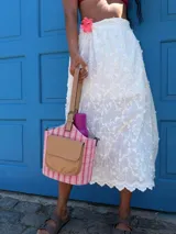 Matero tipo balde con cuerpo de tela a rayas verticales blancas y celestes pálidas. Posee un bolsillo frontal de símil cuero color camel con solapa y logo grabado. Incluye asa de mano y correa larga desmontable.