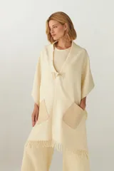 Chal de lana fina sin teñir, con calce en hombros, abrochadura con alamar de fieltro, bolsillos de cuero y terminación con flecos. Diseño exclusivo de Don Baez, hecho en Uruguay.