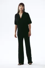 Pantalón negro de tejido de punto con diseño calado en rombos, corte recto y tiro medio.