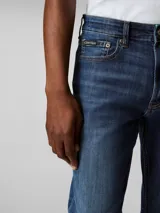 Pantalón de jean azul oscuro, corte slim, con bolsillos delanteros y traseros, cierre con cremallera y botón.