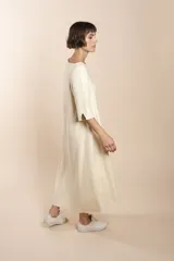 Vestido largo debajo de la rodilla, acampanado, color marrón, con cuello bote, bolsillos laterales y mangas 3/4 con detalle de tajo.