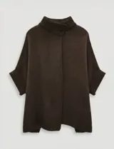 Capa o poncho tejido color verde esmeralda, con cuello polera alto que se cierra con un botón grande en el lateral. Presenta mangas cortas estilo japonesa y un calce amplio.