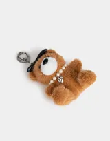 Llavero con dije de oso de peluche color marrón claro, con moño negro, collar de perlas y dije de corazón plateado.