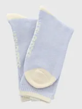 Calcetín de largo medio, tejido grueso, color celeste claro jaspeado, con talón y puntera en color crema. Presenta una etiqueta tejida con el logo de un perro (Basset Hound) en el borde superior.