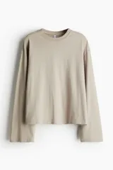 Remera color beige de corte cuadrado, con cuello redondo y mangas largas.