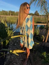 Vestido camisero corto con estampado de rombos en tonos beige, marrón y blanco. Tiene cuello camisero, cierre frontal con botones y corte holgado.