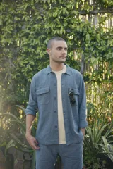 Camisa color verde militar de manga larga con cuello clásico, cierre frontal con botones y dos bolsillos de parche en el pecho.