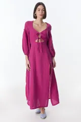 Vestido color beige de lino, con escote en V, mangas largas abullonadas y lazos frontales. Tiene corte a la cintura y falda larga con tajo frontal.