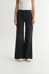 Pantalón jean negro de corte holgado, levemente ajustado en cintura y cadera, con pierna ancha y ruedo desflecado.