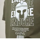 Remera verde militar de algodón con estampado en la espalda con la palabra "ENDURE" repetida y un casco espartano. Incluye una frase motivacional y el logo "GAINS."
