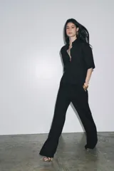 Camisa negra de manga corta confeccionada en hilatura con lyocell y ramio, con cuello solapa, bajo recto y cierre frontal con botones.