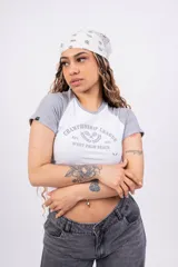 Remera corta blanca con mangas raglán negras, cuello redondo y estampado frontal con el texto "Championship League Est. 1996 West Palm Beach" y dos raquetas de tenis cruzadas.