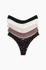 Pack de cinco bombachas colaless de algodón en colores negro, blanco, beige, marrón y negro con estampado floral. Todas con detalle de moño en el centro.