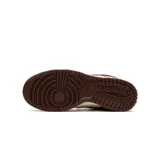 Zapatillas Nike Dunk Low, color blanco y marrón chocolate, con cordones marrones y suela color crema.