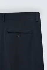 Pantalón de vestir gris oscuro, corte slim fit, confeccionado en tejido con 17% de lana. Cuenta con bolsillos frontales y traseros de vivo con botón. Cierre frontal con cremallera y botón.