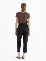 Pantalón negro de tiro alto, estilo mom fit, confeccionado en poplin con spandex. Presenta tablas en la cintura con cinto de hebilla de cadena dorada, canesú y pinzas delanteras.
