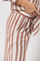Pantalón de corte recto, con cintura elastizada y bolsillos laterales. Diseño a rayas verticales color marrón y blanco.