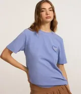 Remera celeste de corte amplio, con cuello redondo y mangas cortas. Estampado en la espalda con un corazón y texto en color azul.