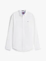 Camisa blanca de manga larga, confeccionada en mezcla de algodón y lino. Tiene corte regular, cuello abotonado, cierre con botones y logo de Tommy Jeans bordado en el pecho.