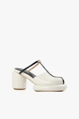 Mules de cuero color blanco con diseño moderno, taco ancho y plataforma. Cuenta con una tira superior negra que aporta estabilidad y un calce cómodo.